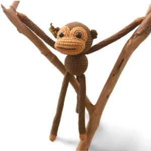 Adorable crocheted monkey with floppy ears and a playful smile.